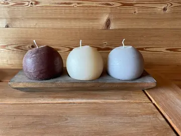 3 bougies rondes sur socle rectangulaire en bois.