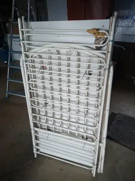 Lit bébé à barreaux métal avec barrière relevable.