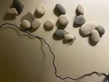 une quinzaine de galets collés sur grillage plastique