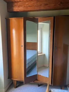 Une armoire avec miroir et son lit avec sommier sans matelas