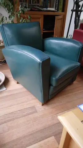 Donne deux fauteuils : un fauteuil club en cuir vert et un fauteuil rouge en tissu.